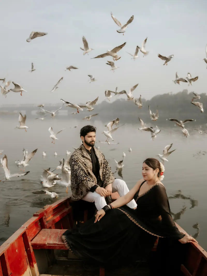 Couple sitting in a wooden boat on a misty lake as gulls fly around them