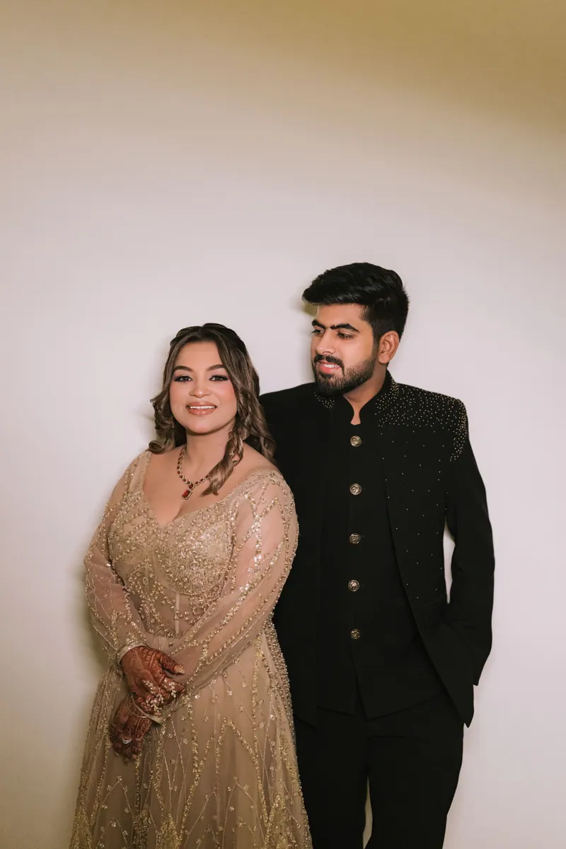 Bride in a champagne gown and groom in a black bandhgala standing together