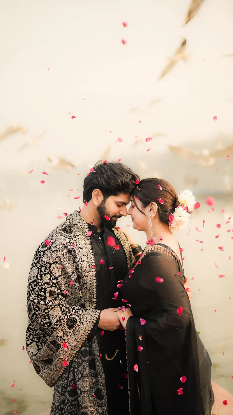 Couple with foreheads touching as rose petals fall around them